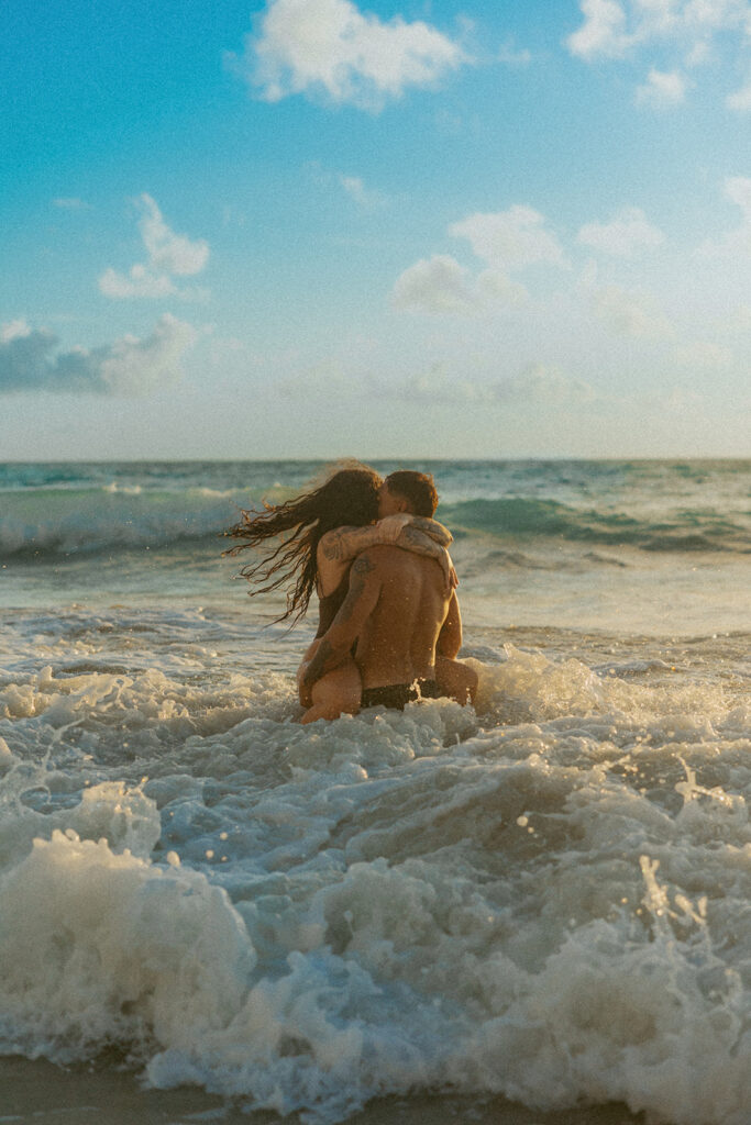 Couple laughing and playing in the ocean during an Oahu couples photoshoot at sunrise