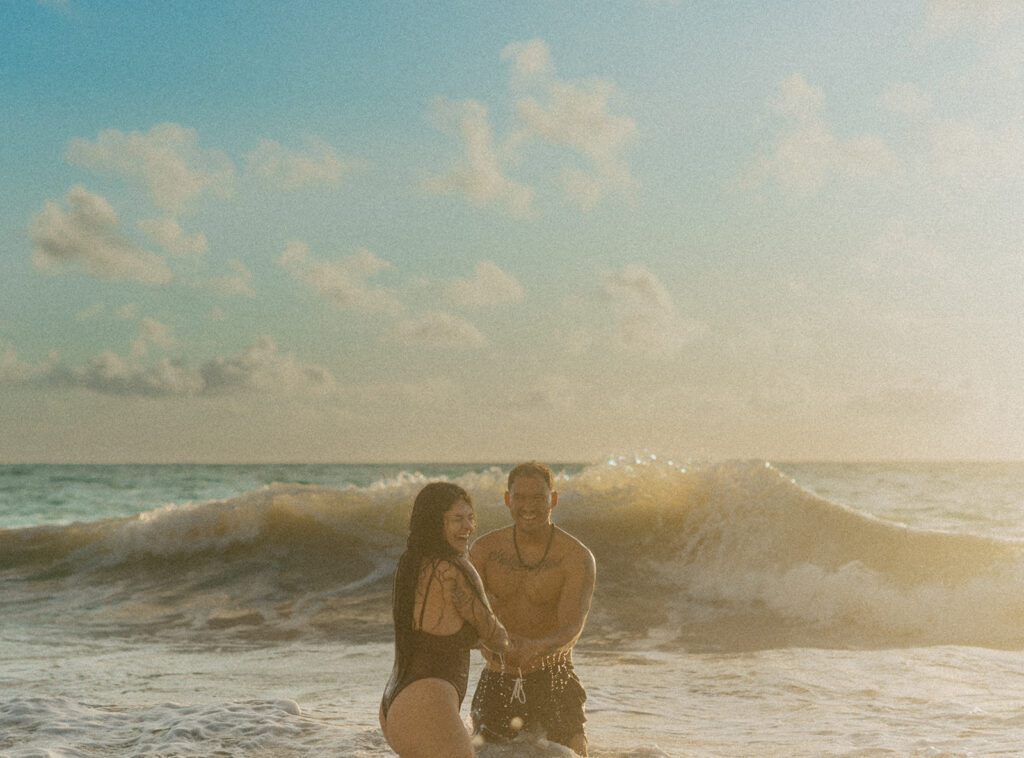 Playful couples session on the shore with golden morning light in Oahu

