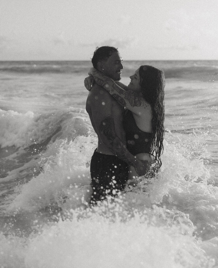 Romantic beach photoshoot with couple embracing in the waves in Hawaii

