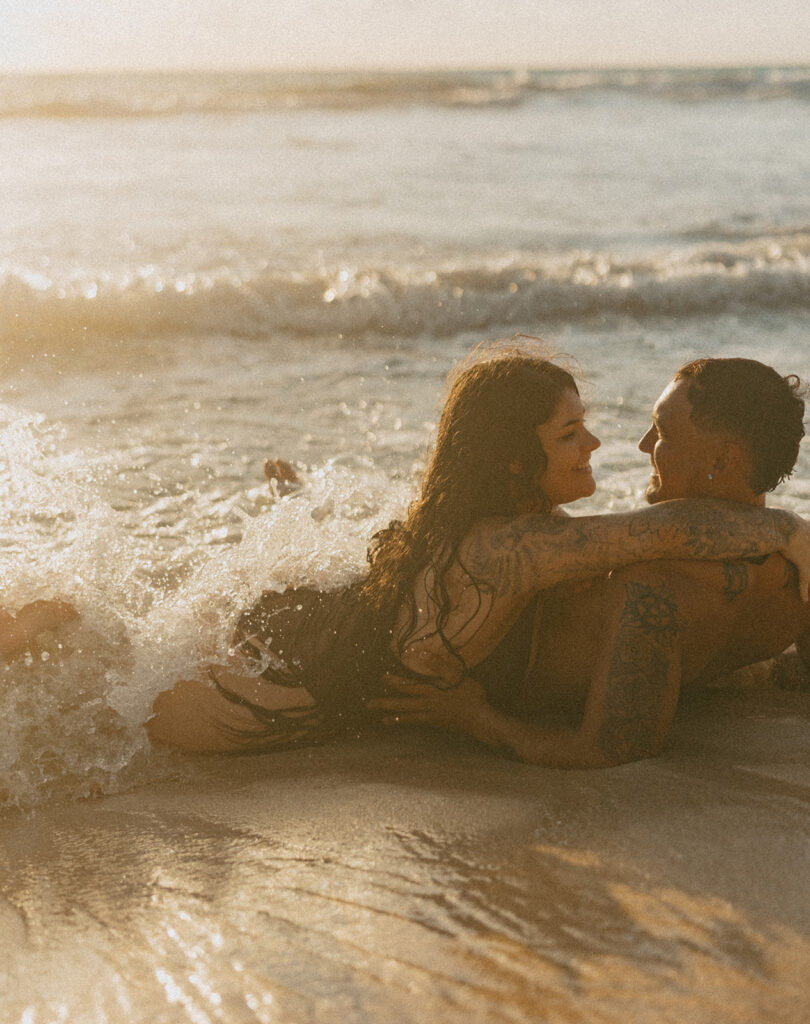 Playful couples session on the shore with golden morning light in Oahu

