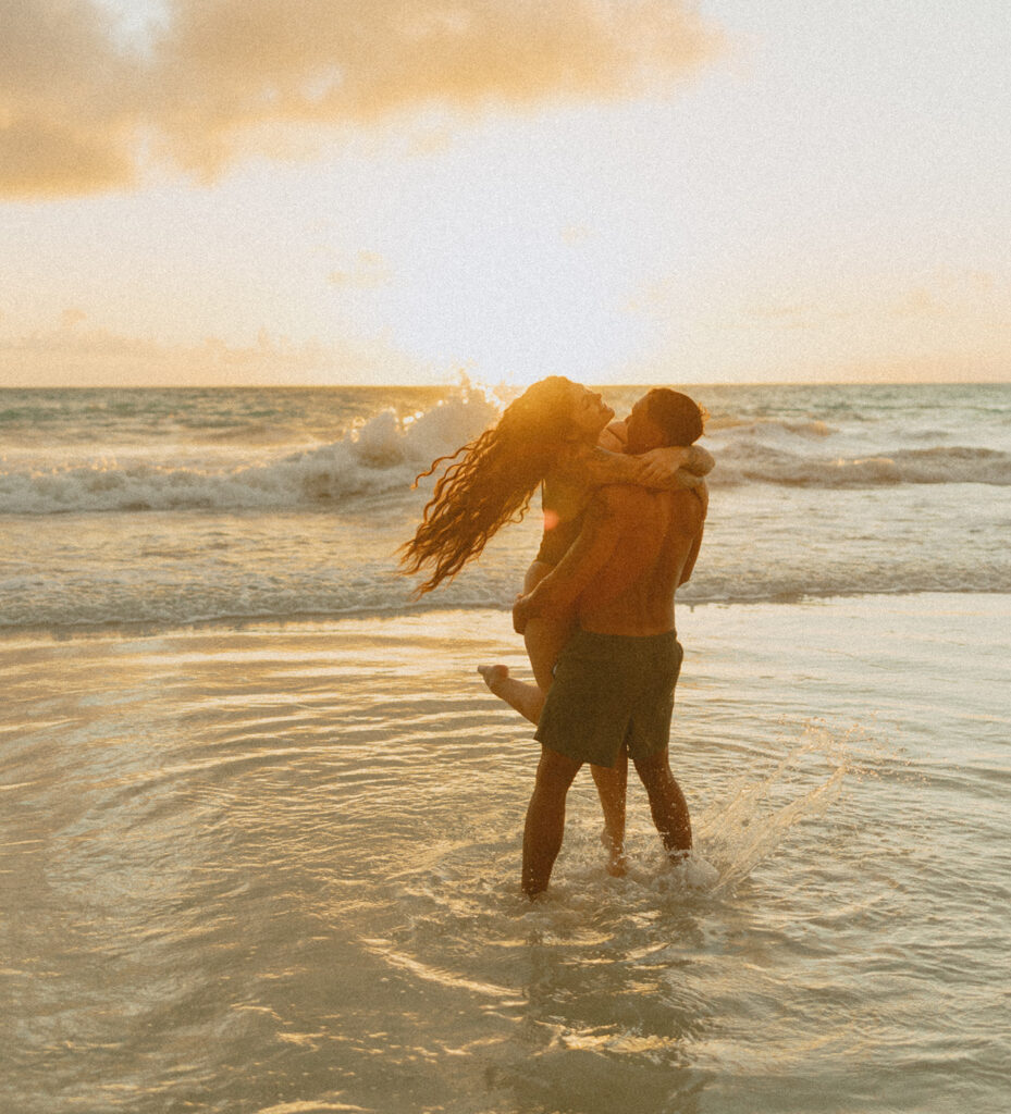 Couple holding hands and running along the beach during an Oahu couples photoshoot
