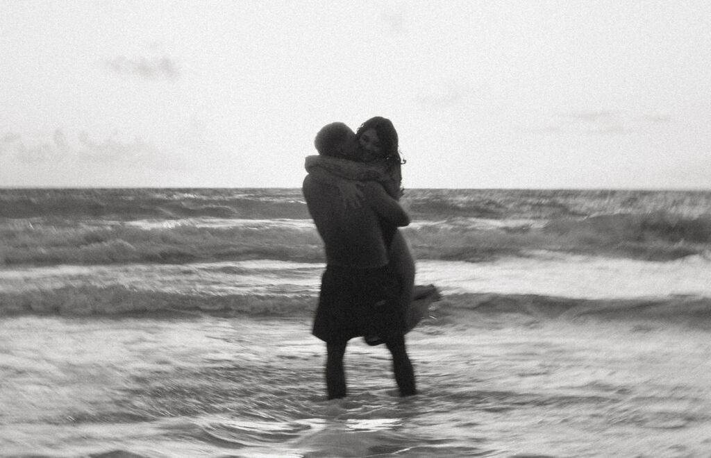 Romantic beach photoshoot with couple embracing in the waves in Hawaii
