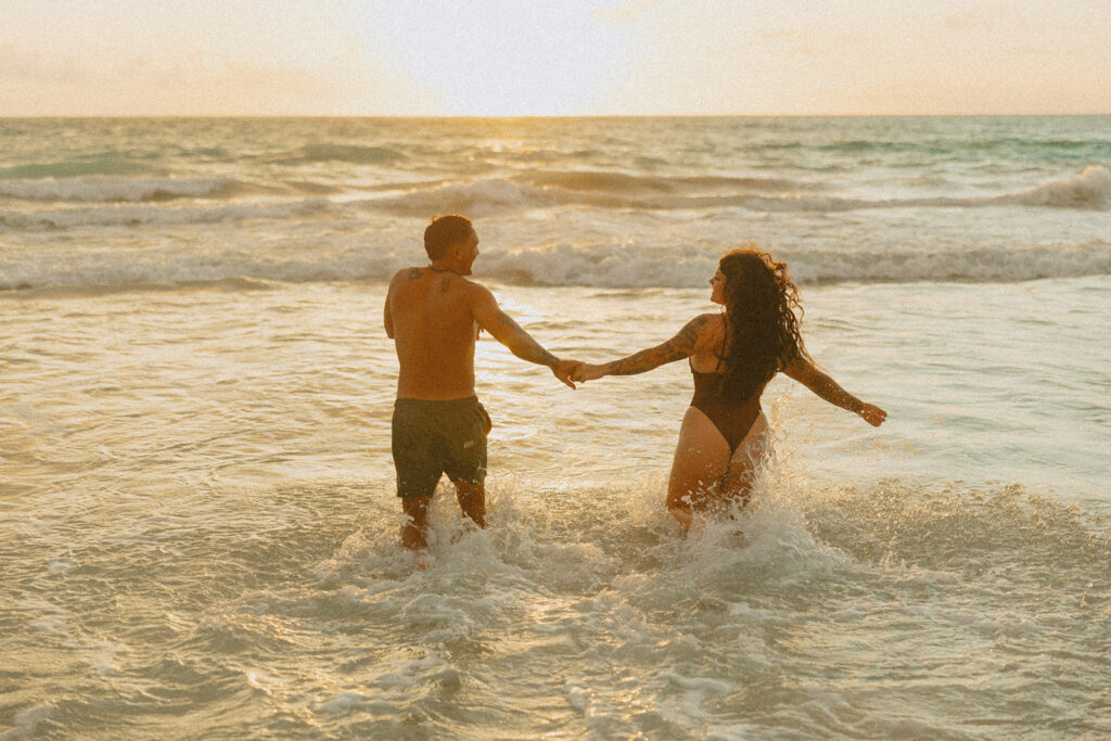 Romantic beach photoshoot with couple embracing in the waves in Hawaii
