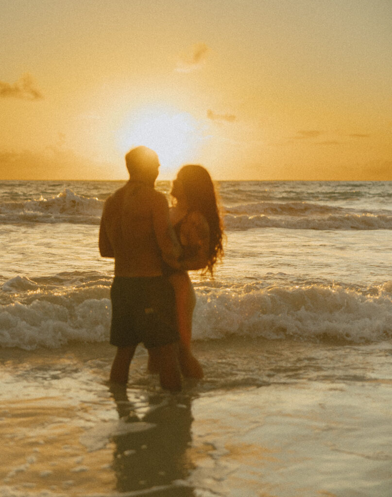 Playful couples session on the shore with golden morning light in Oahu
