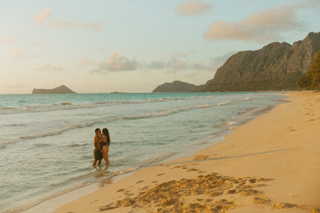 Romantic beach photoshoot with couple embracing in the waves in Hawaii
