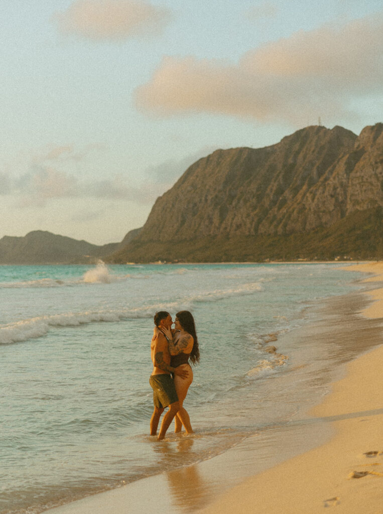 Playful couples session on the shore with golden morning light in Oahu
