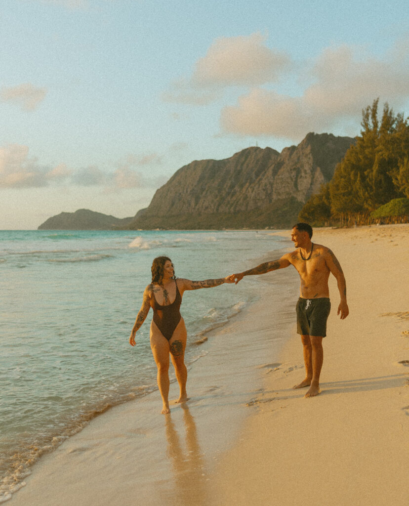 Playful couples session on the shore with golden morning light in Oahu
