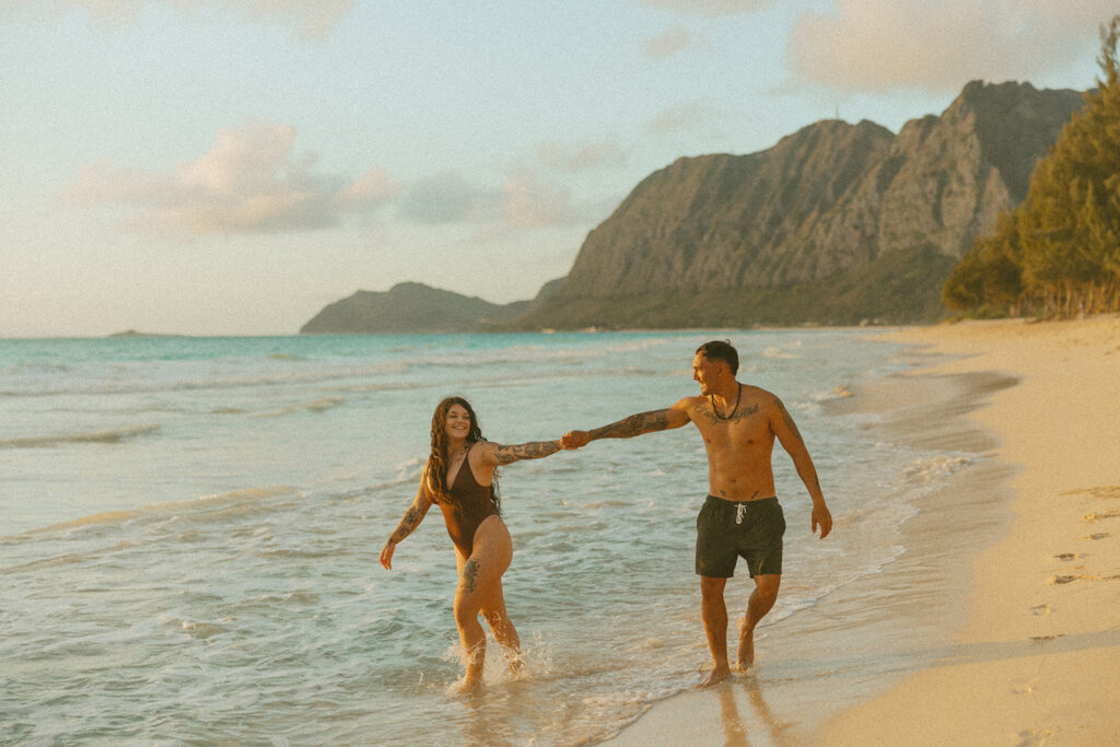 Playful couples session on the shore with golden morning light in Oahu
