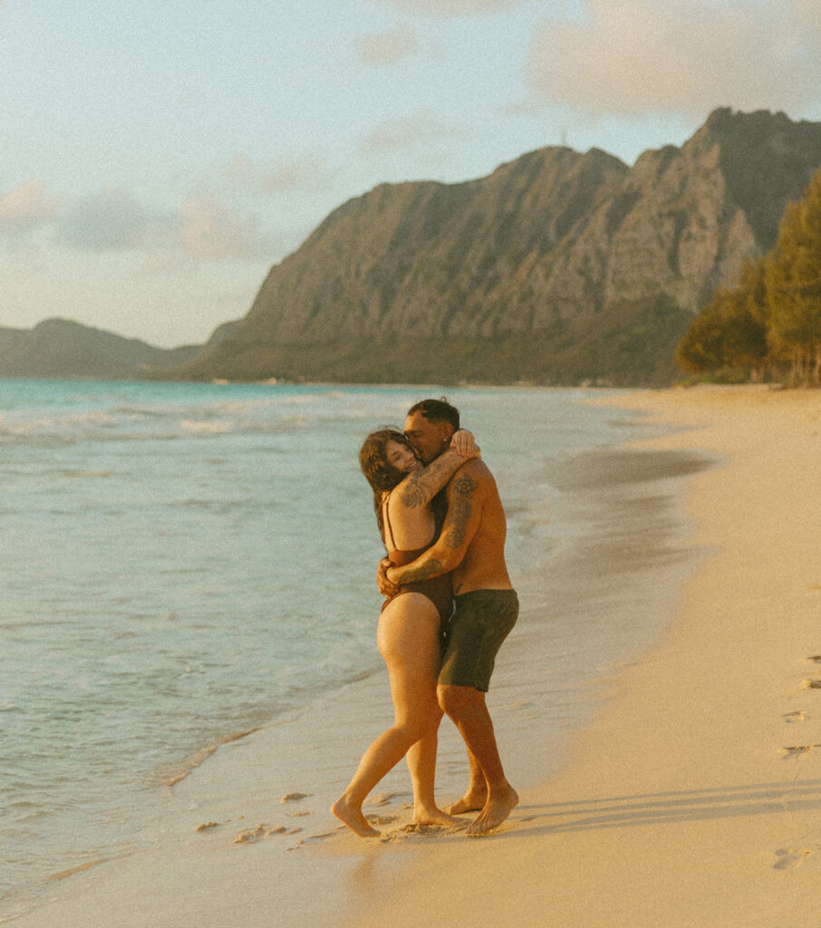 Couple laughing and playing in the ocean during an Oahu couples photoshoot at sunrise
