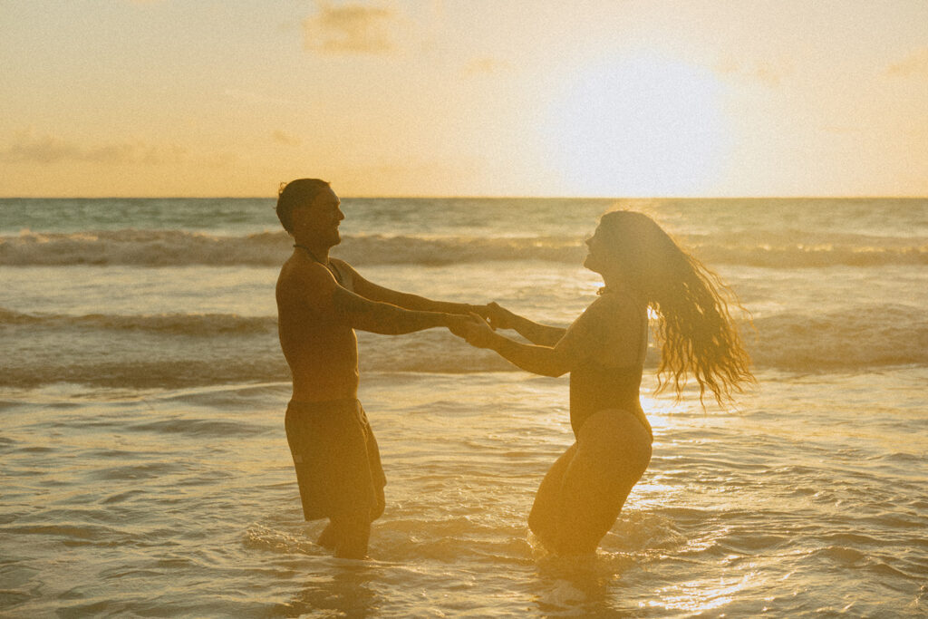 Playful couples session on the shore with golden morning light in Oahu
