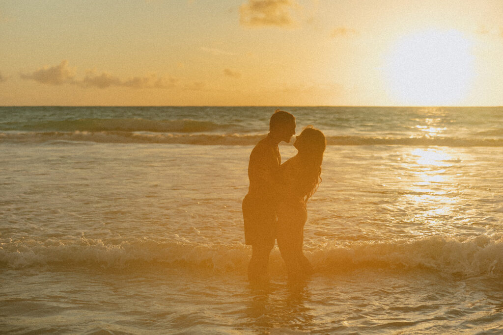 Playful couples session on the shore with golden morning light in Oahu
