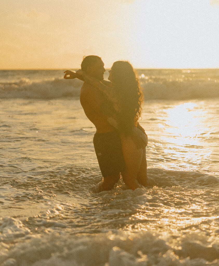 Playful couples session on the shore with golden morning light in Oahu