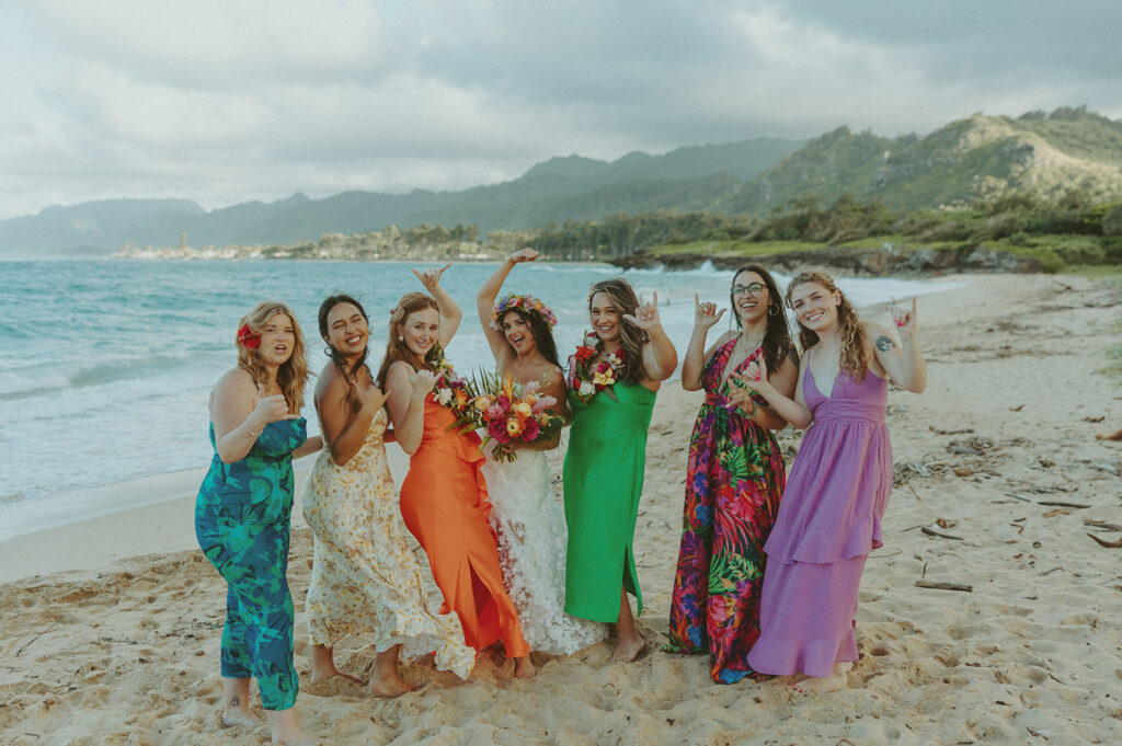 Bride and groom celebrating with their wedding party along the ocean shoreline.

