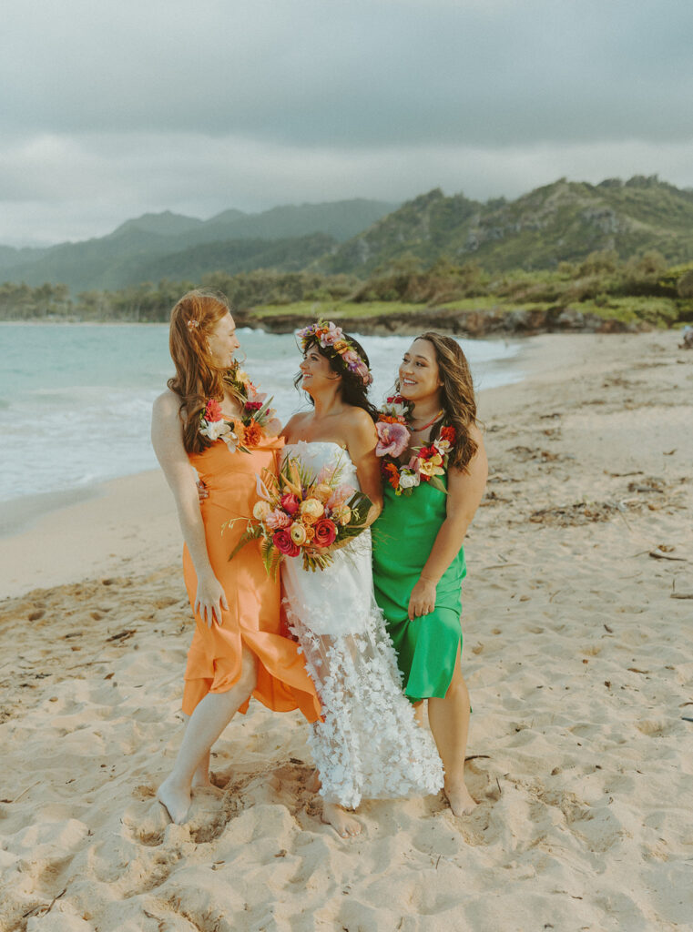 Bride and groom celebrating with their wedding party along the ocean shoreline.
