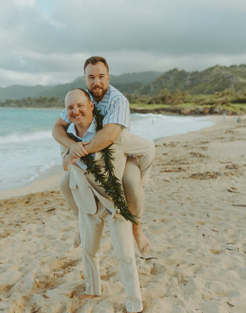 Bride and groom celebrating with their wedding party along the ocean shoreline.
