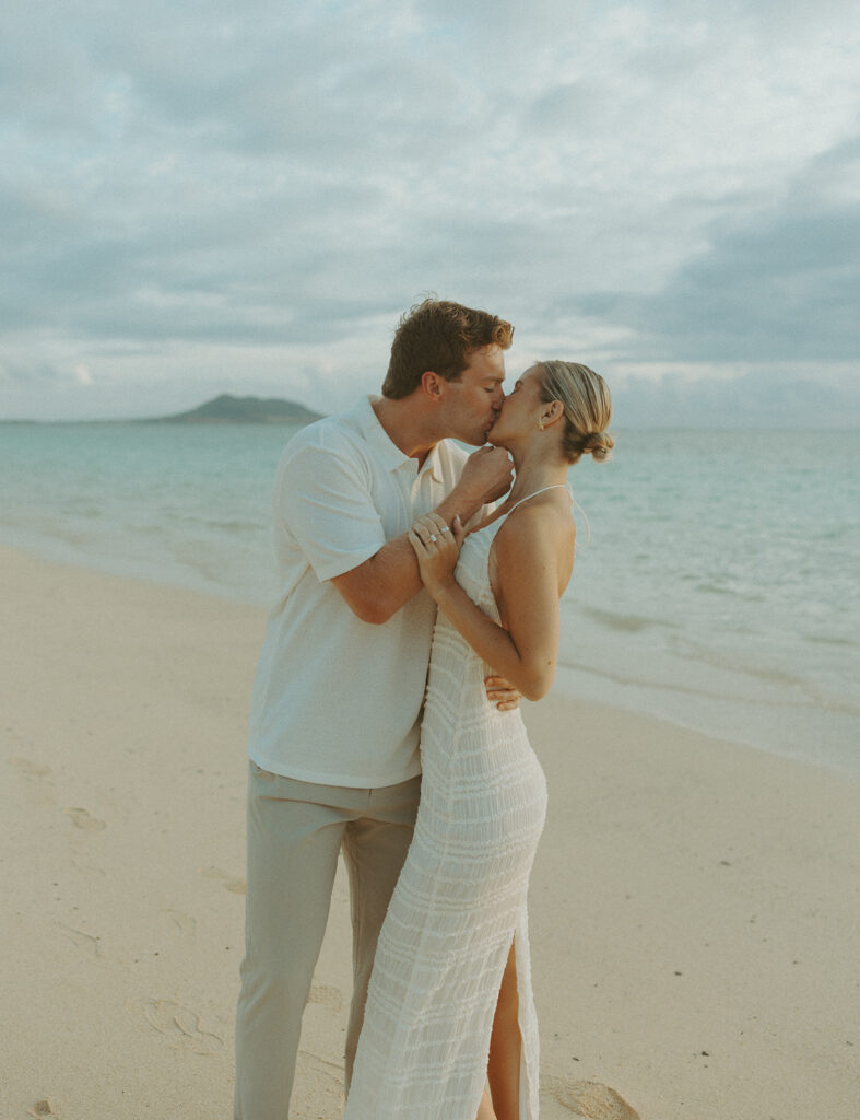 Couple embracing after a surprise proposal during golden hour by the water
