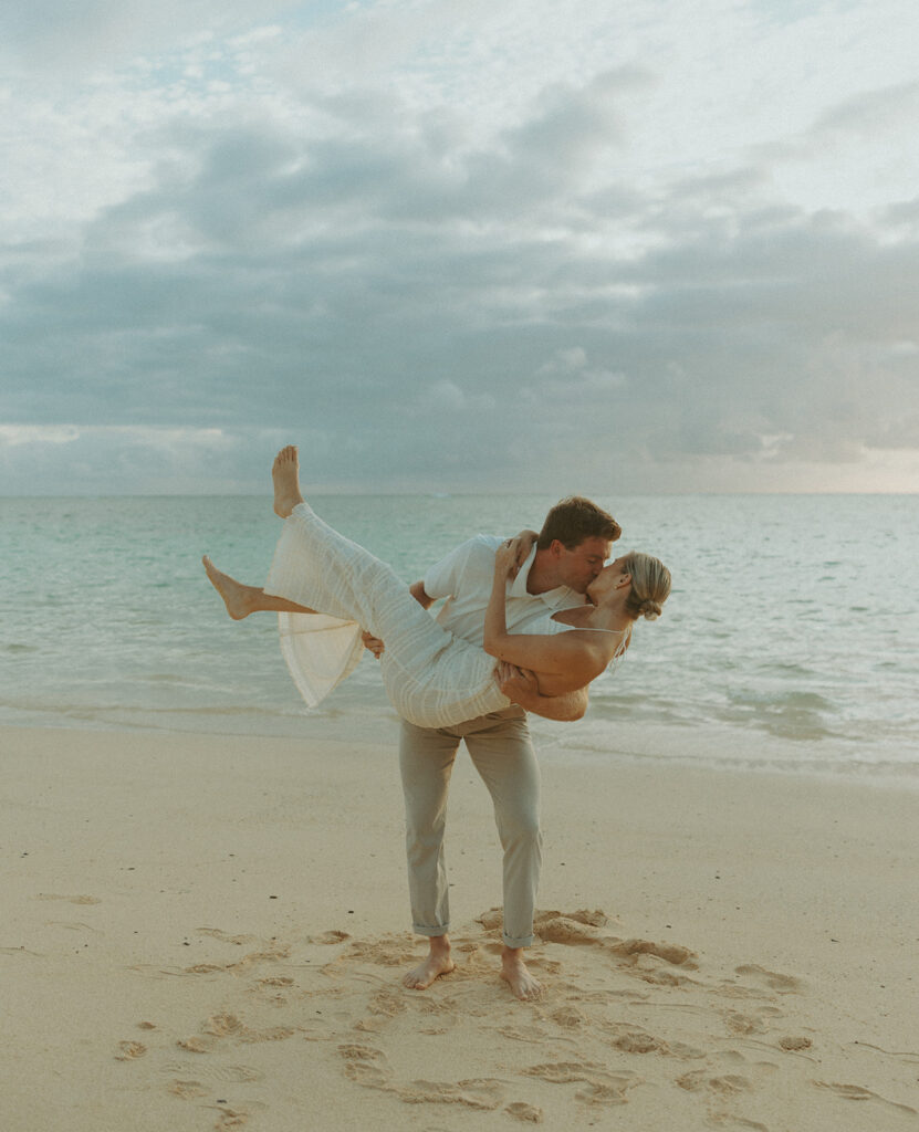 Couple embracing after a surprise proposal during golden hour by the water
