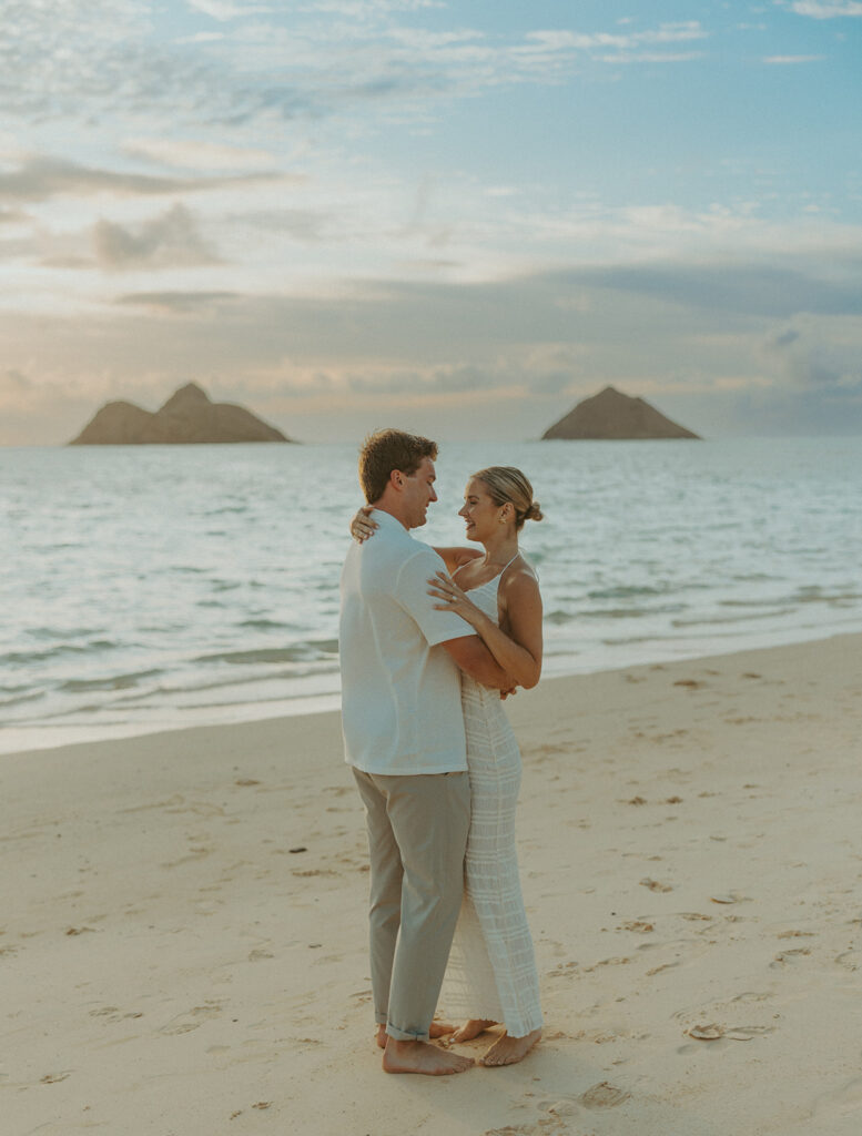 Couple embracing after a surprise proposal during golden hour by the water
