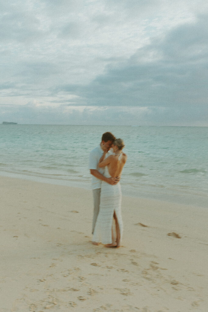 Couple embracing after a surprise proposal during golden hour by the water

