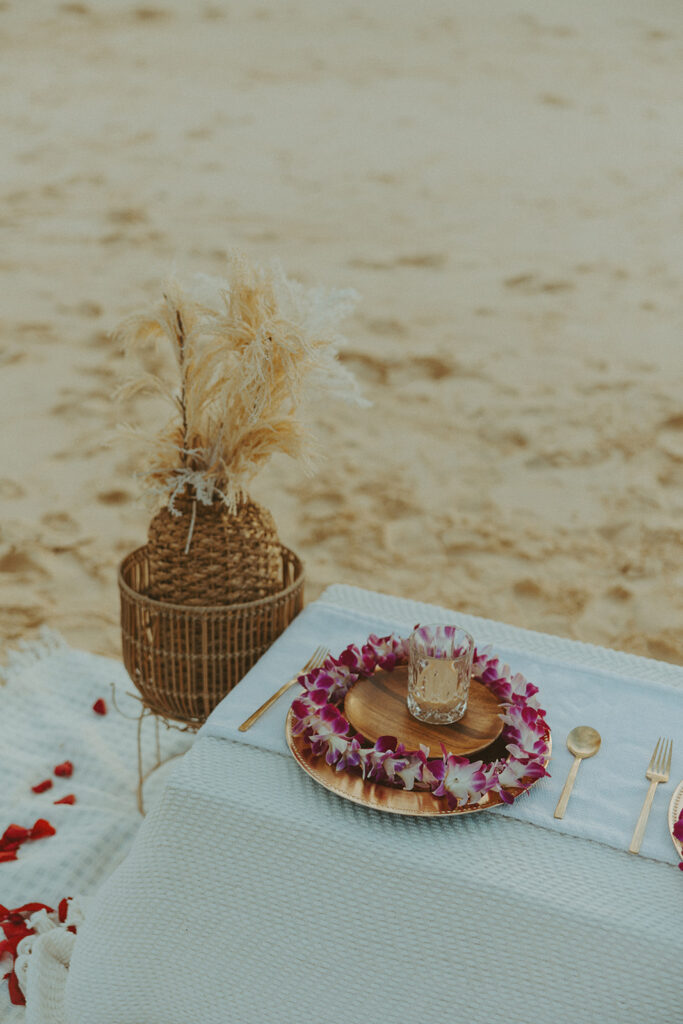 Sunrise light reflecting on a beachside picnic setup with flowers and blankets
