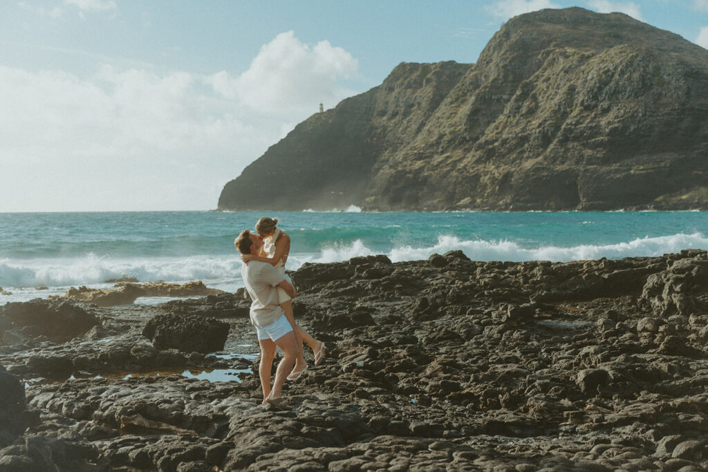 Romantic moment captured on the sand with ocean waves in the background
