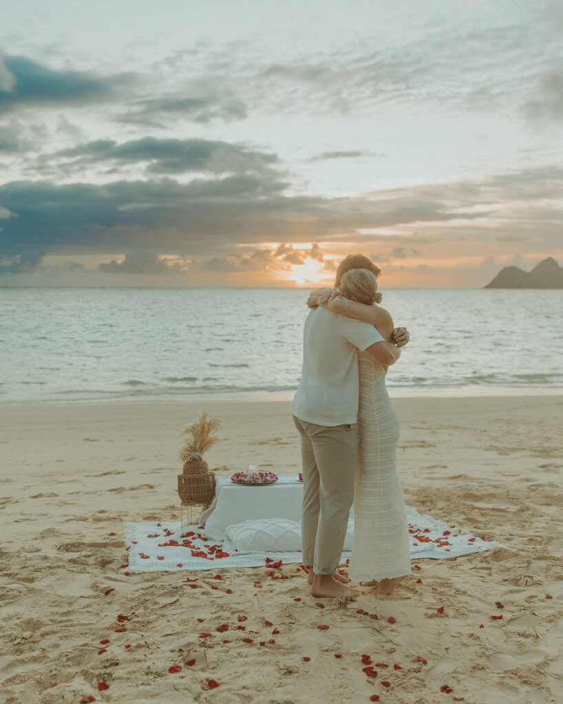 Couple sharing a sunrise picnic proposal on a quiet beach in Hawaii
