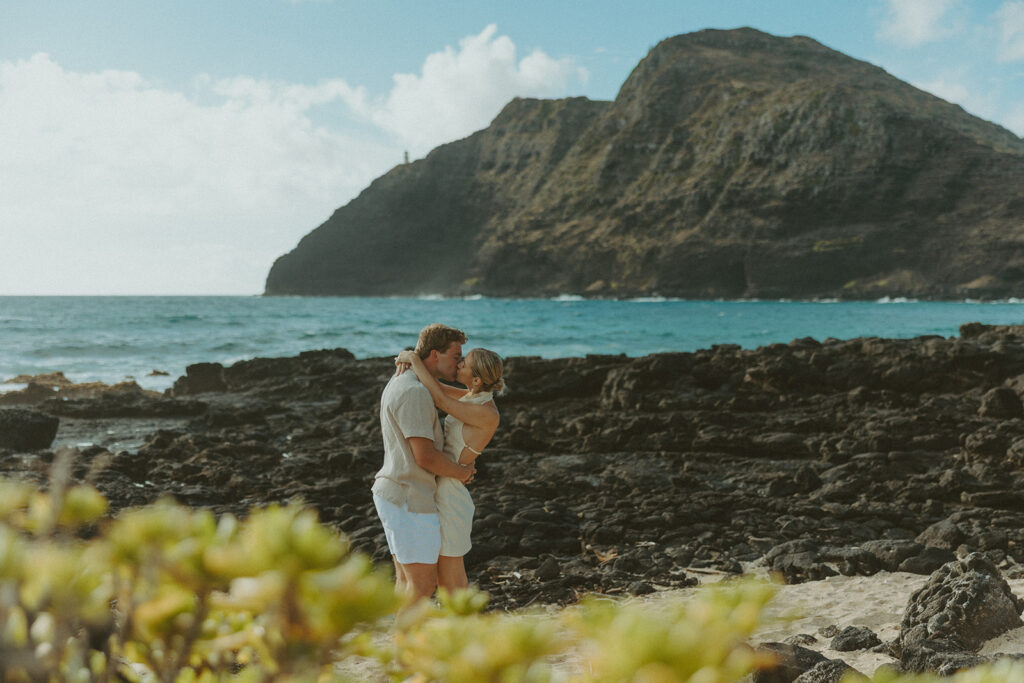 Romantic moment captured on the sand with ocean waves in the background
