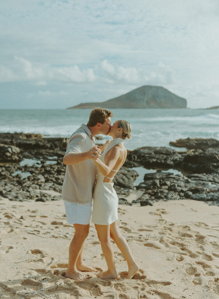 Romantic moment captured on the sand with ocean waves in the background
