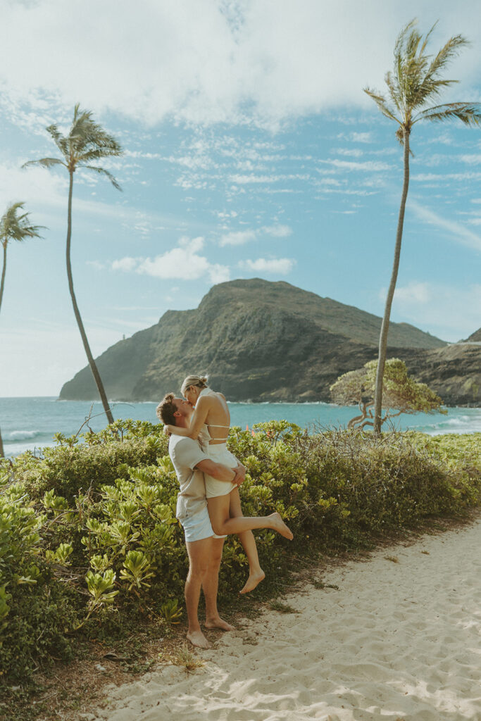 Romantic moment captured on the sand with ocean waves in the background
