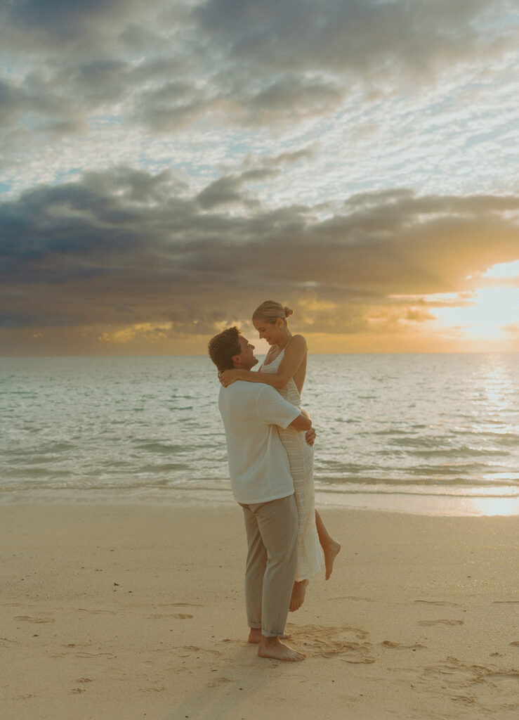 Romantic moment captured on the sand with ocean waves in the background
