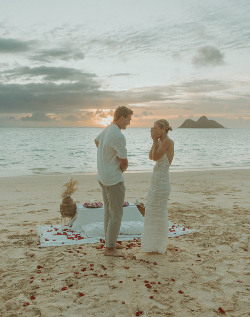 Couple sharing a sunrise picnic proposal on a quiet beach in Hawaii