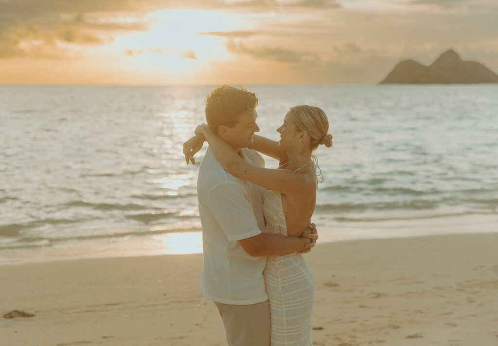 Romantic moment captured on the sand with ocean waves in the background
