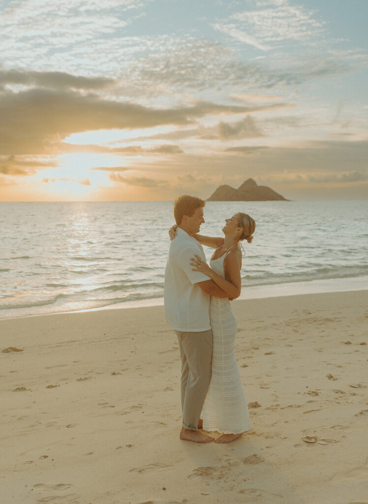 Couple embracing after a surprise proposal during golden hour by the water | Lanikai Beach Proposal