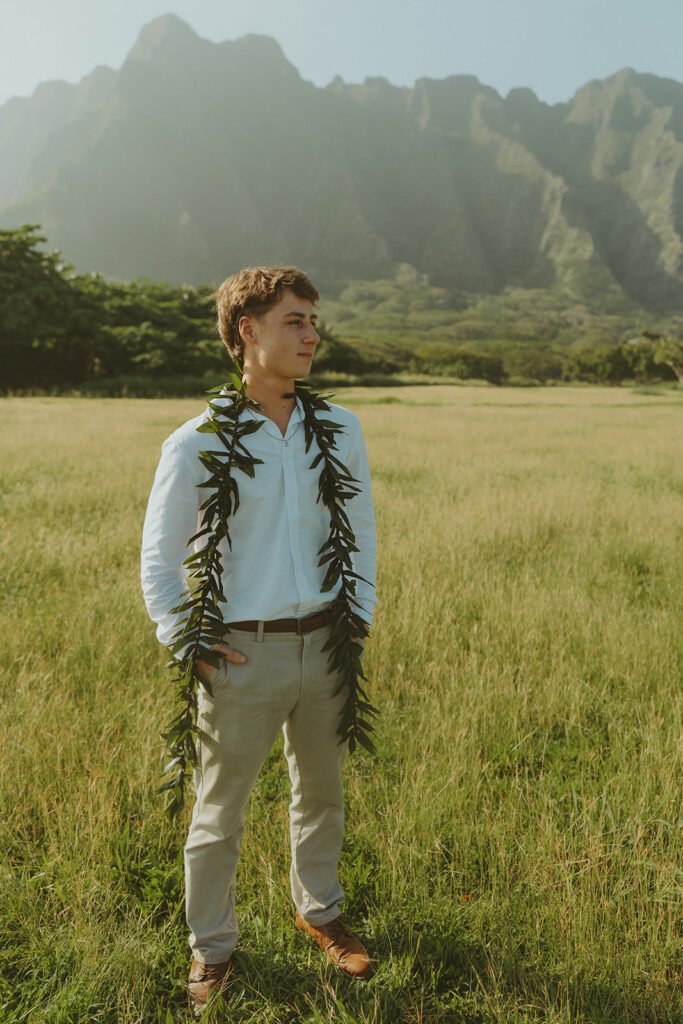 Bride and groom walking through Kualoa Regional Park with mountain views in the background.
