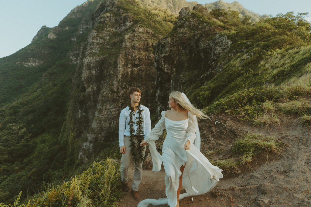 Couple hiking up the Crouching Lion trail surrounded by lush Oahu scenery.
