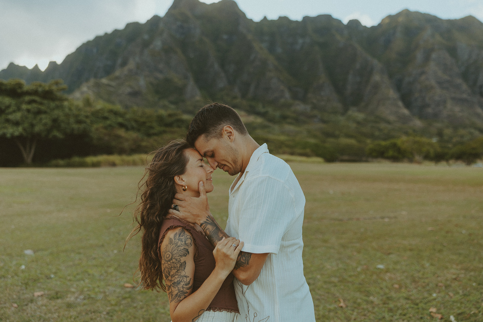 Couple walking along the shoreline at Kualoa Regional Park with ocean and mountain views in the background