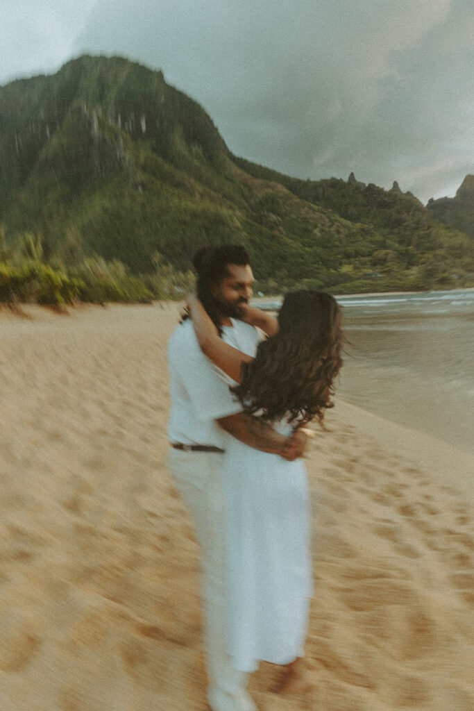 Candid engagement photos of a couple at Tunnels Beach in Kauai during golden hour