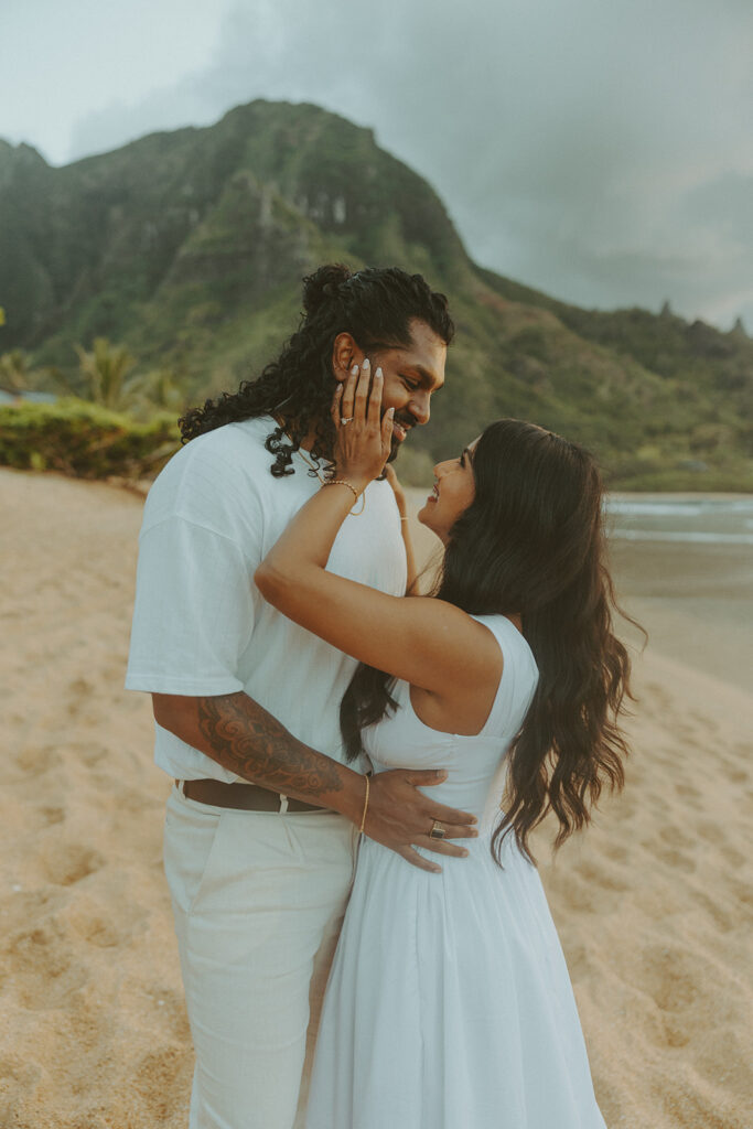 Candid engagement photos of a couple at Tunnels Beach in Kauai during golden hour