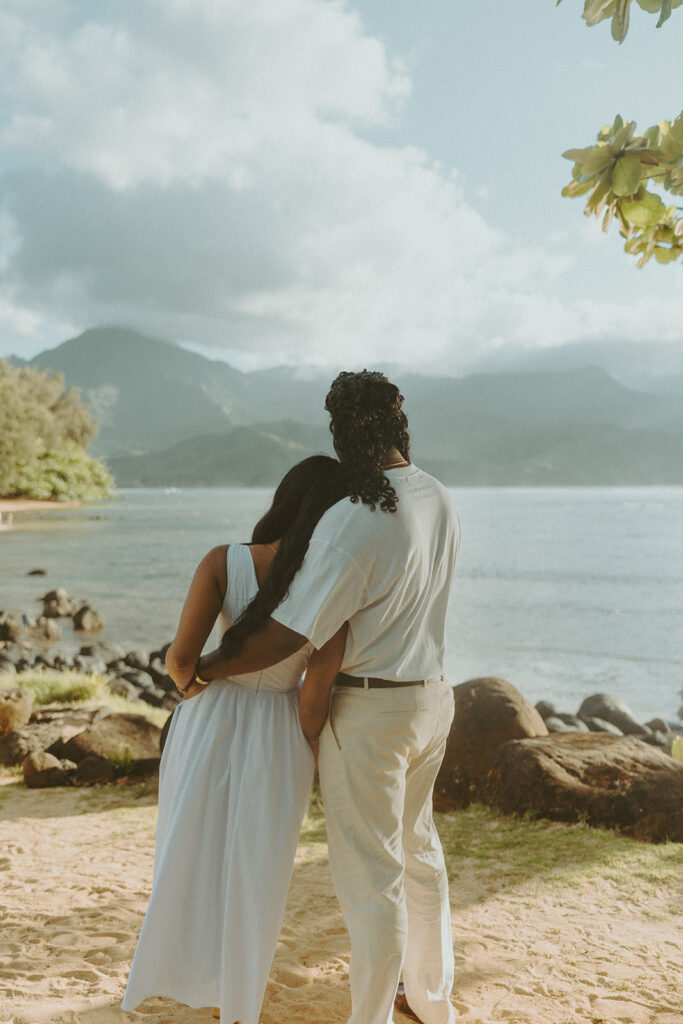 Candid engagement photos of a couple at Tunnels Beach in Kauai during golden hour