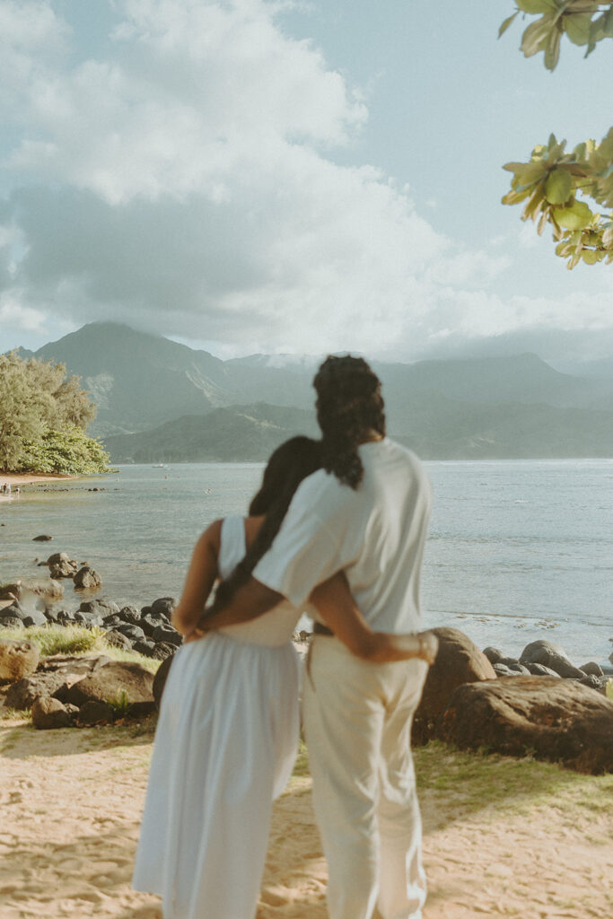 Candid engagement photos of a couple at Tunnels Beach in Kauai during golden hour