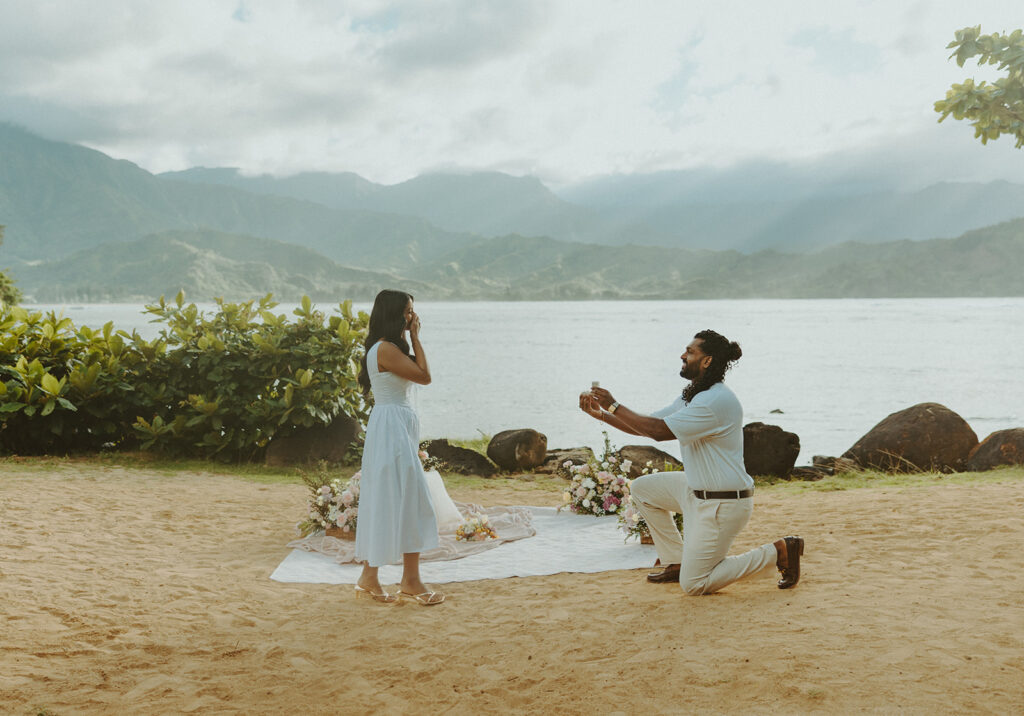 Romantic proposal setup with picnic details and flowers near the water at 1 Hotel Hanalei Bay