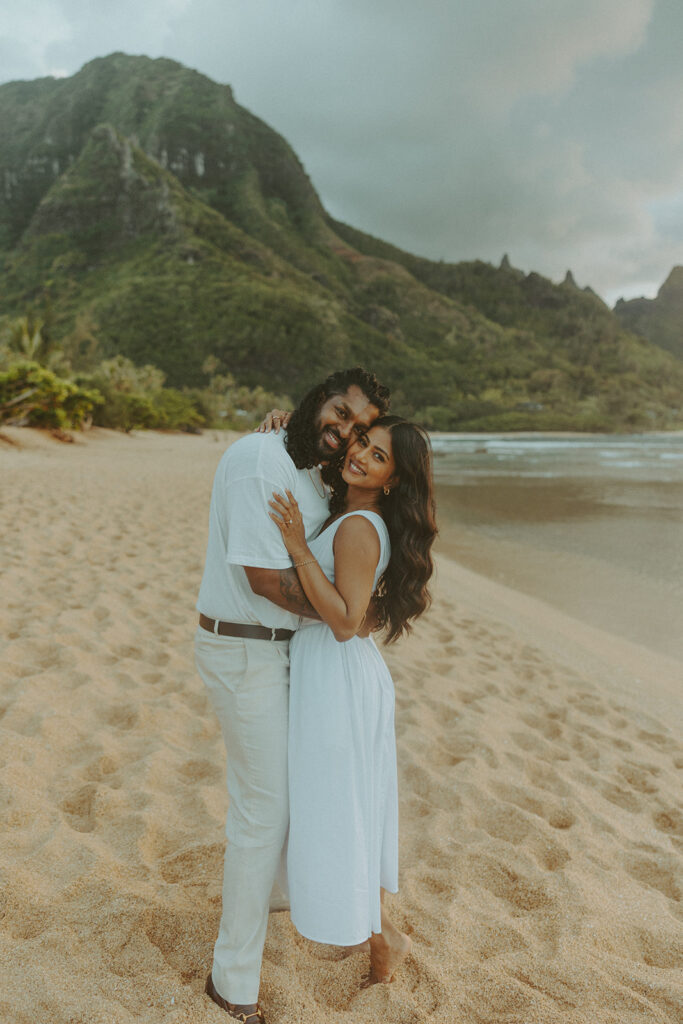 Candid engagement photos of a couple at Tunnels Beach in Kauai during golden hour