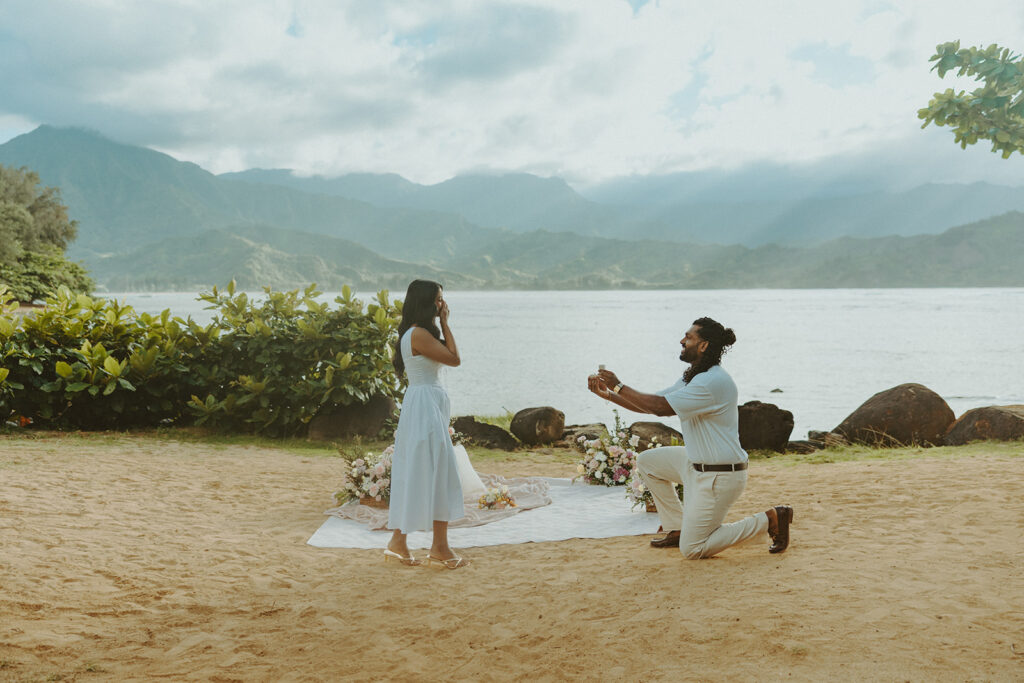 Romantic proposal setup with picnic details and flowers near the water at 1 Hotel Hanalei Bay