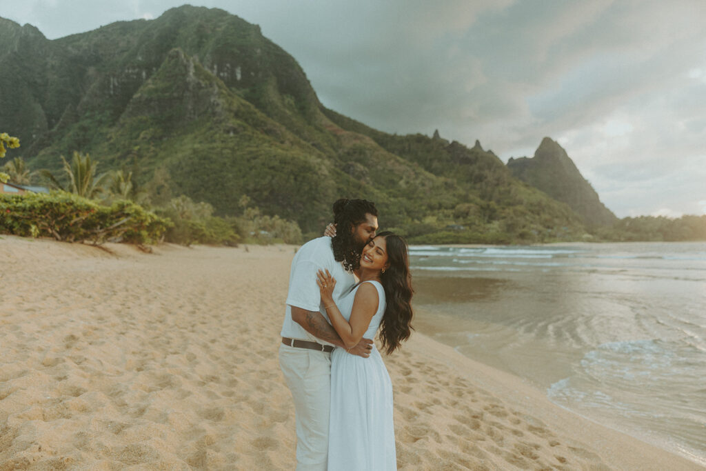 Candid engagement photos of a couple at Tunnels Beach in Kauai during golden hour