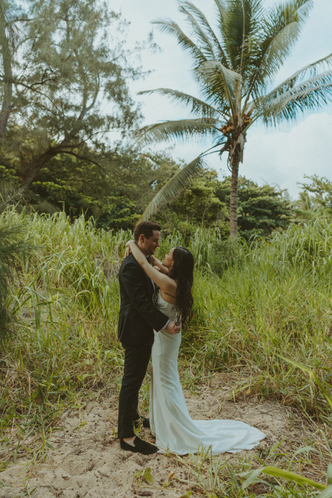 Newlyweds walking hand in hand along the cliffs at Shipwreck Beach during their Kauai elopement
