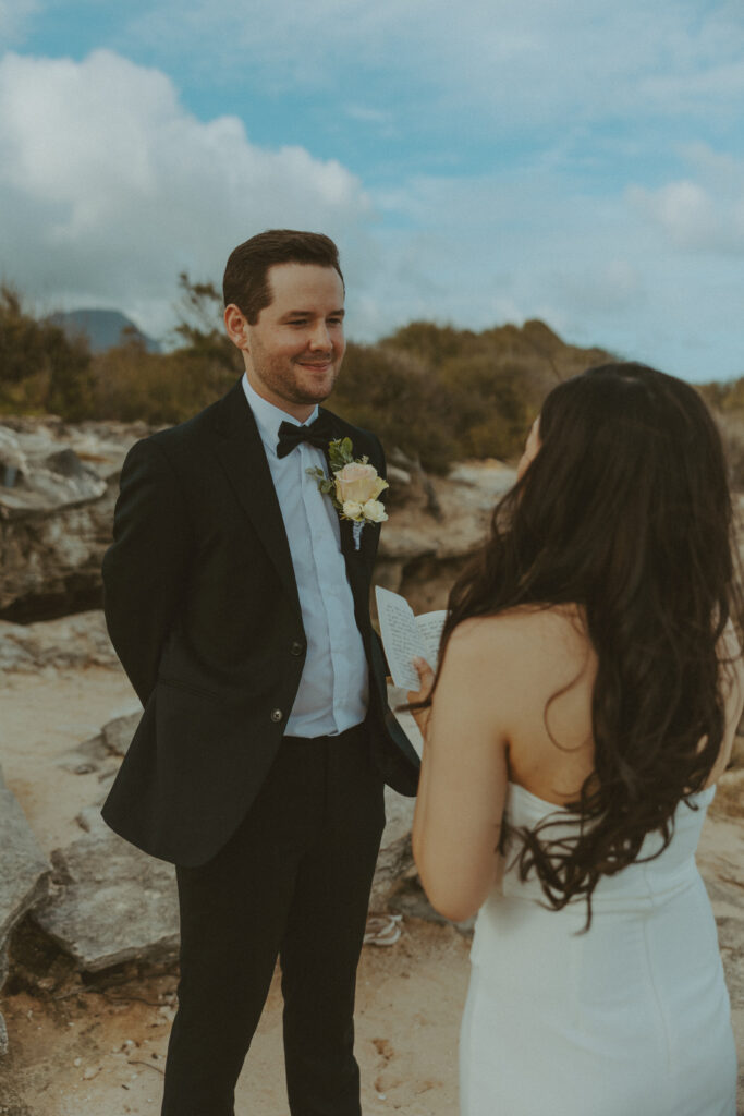 Bride and groom holding hands and smiling after their Shipwreck Beach elopement with ocean waves behind them
