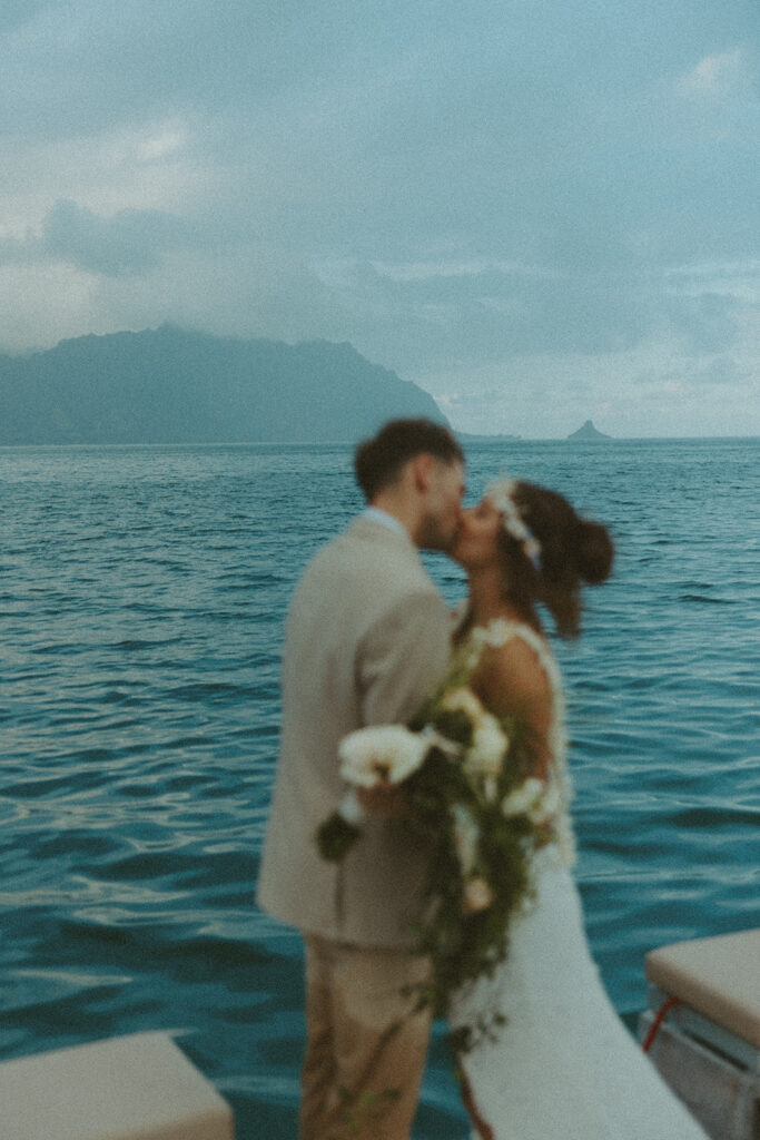Couple holding hands in the water with mountains in the background
