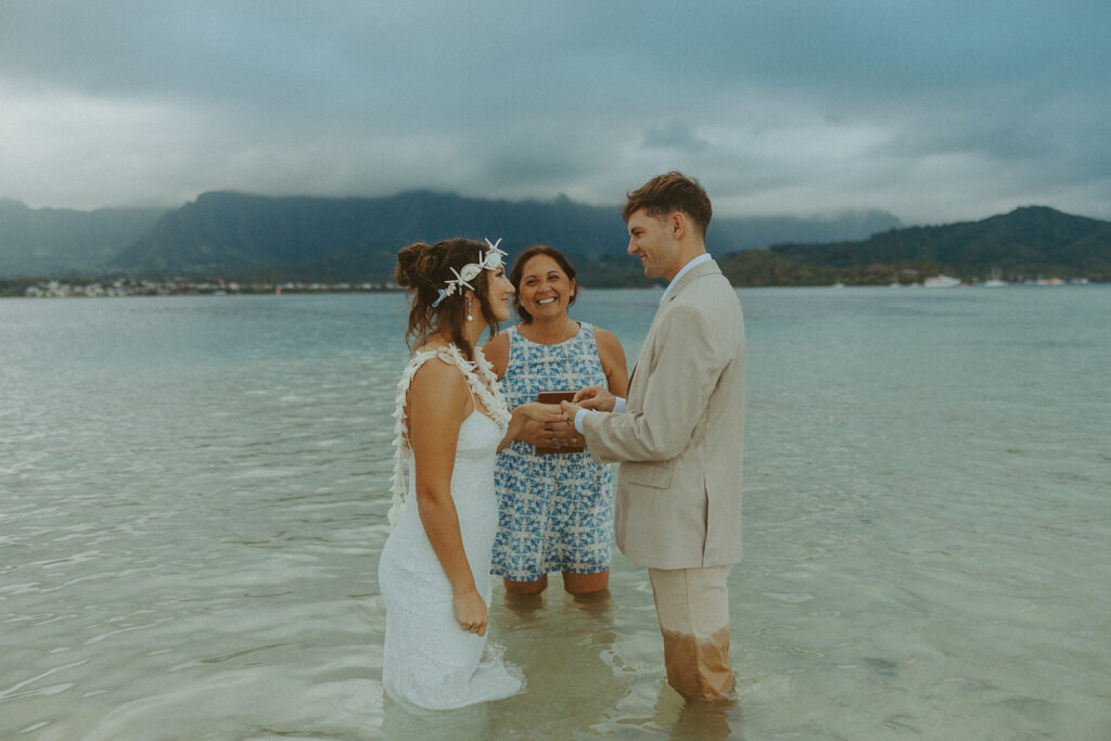 Bride and groom standing in shallow ocean water during a beach wedding ceremony