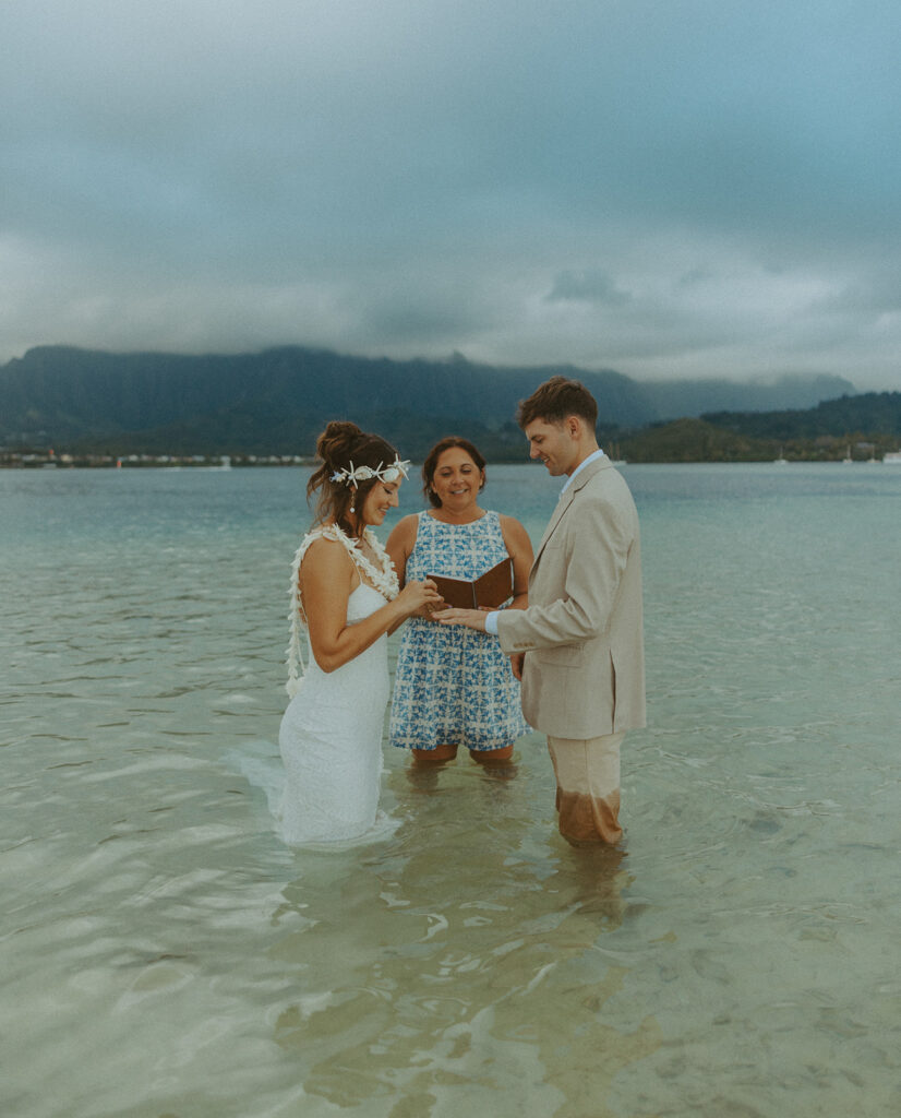 Bride and groom standing in shallow ocean water during a beach wedding ceremony
