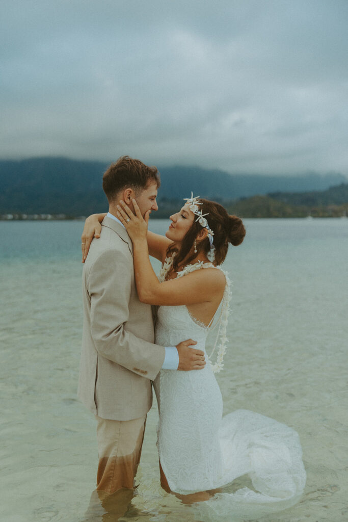 Bride and groom standing in shallow ocean water during a beach wedding ceremony